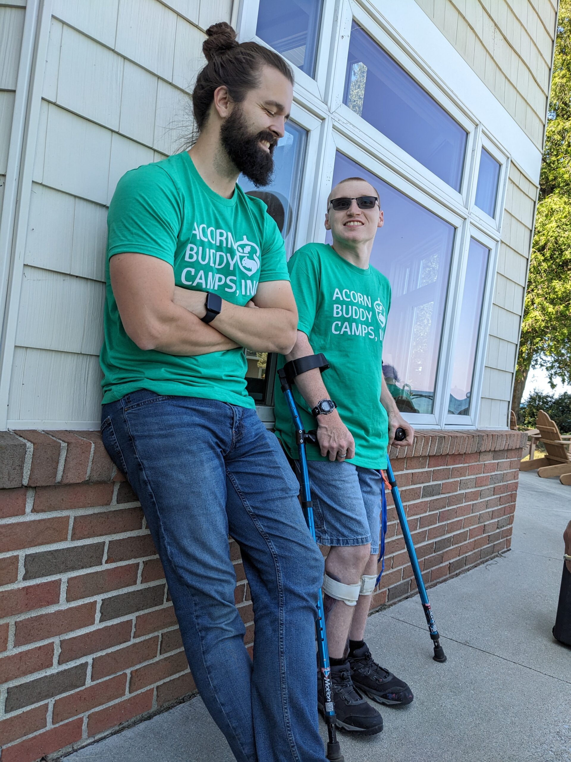 Two counselors next to each other outside leaning against the retreat center talking to each other.