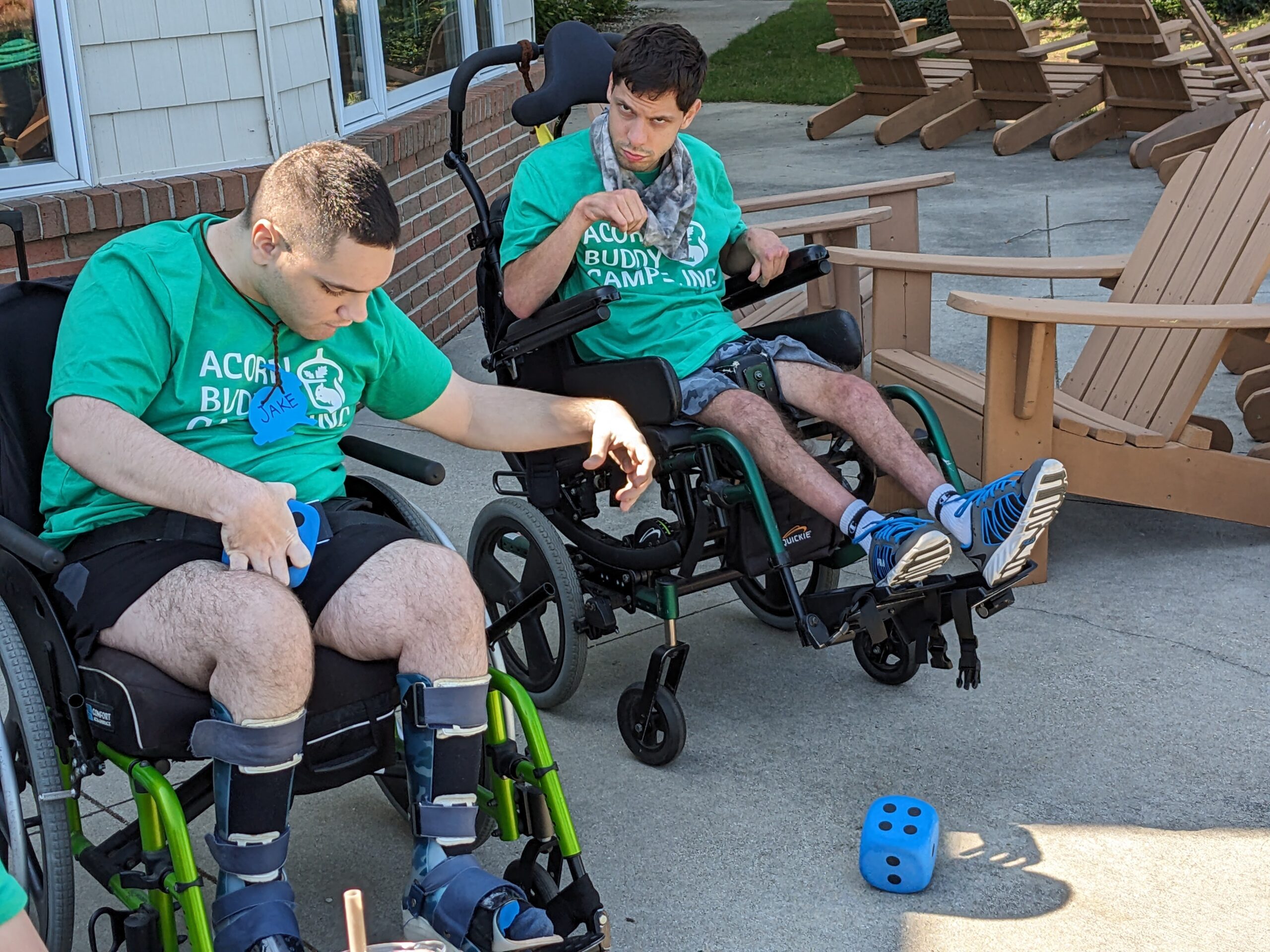 Two campers in their wheelchairs playing yahtzee with adaptive dice.